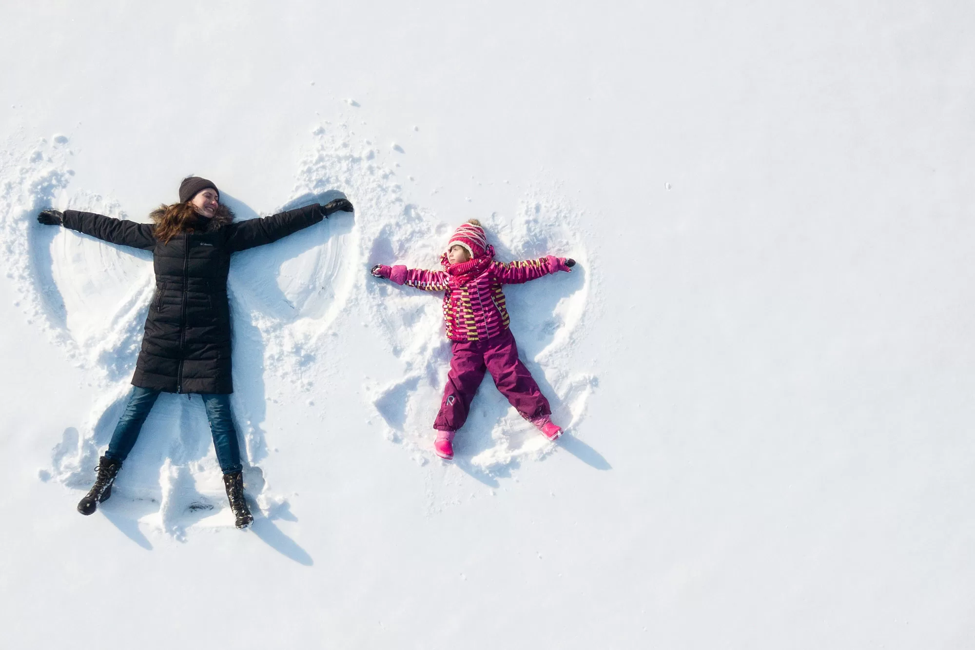 Mom and kid making snow angels - relaxed and having fun because Advantage OIl makes winter easy.